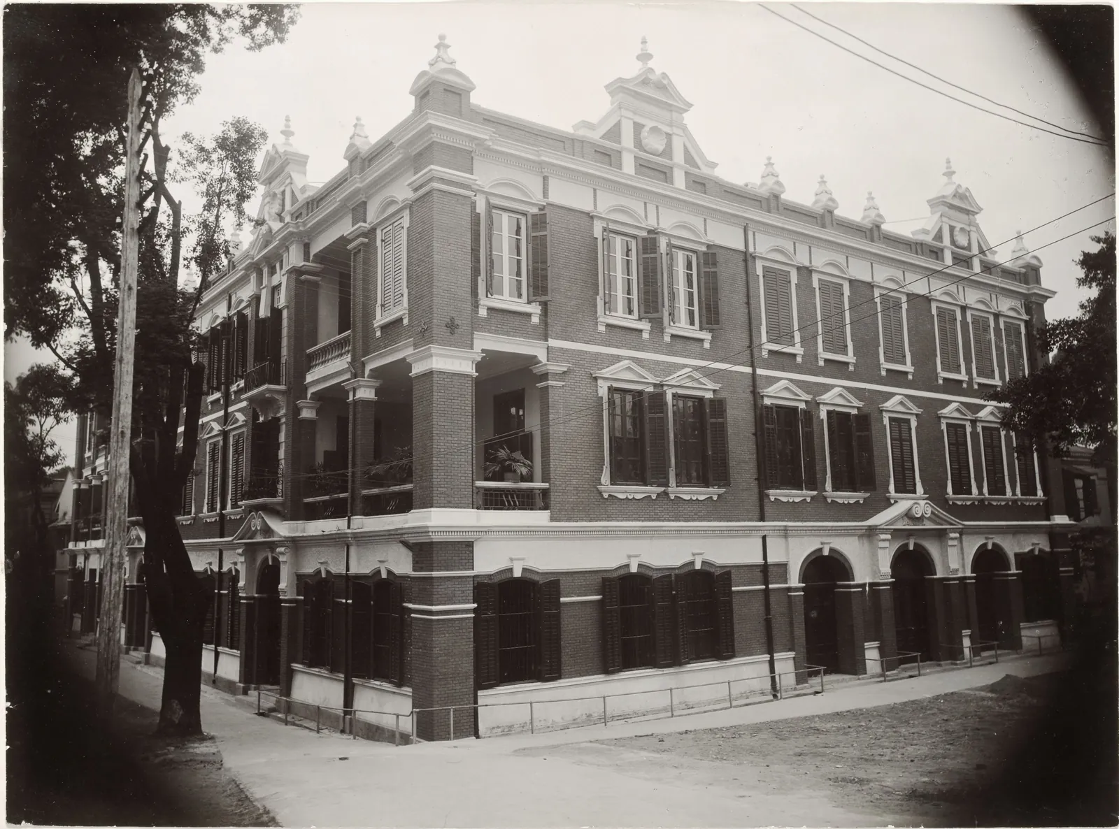 A three-storey brick and stucco corner building with Dutch gables and shuttered windows.