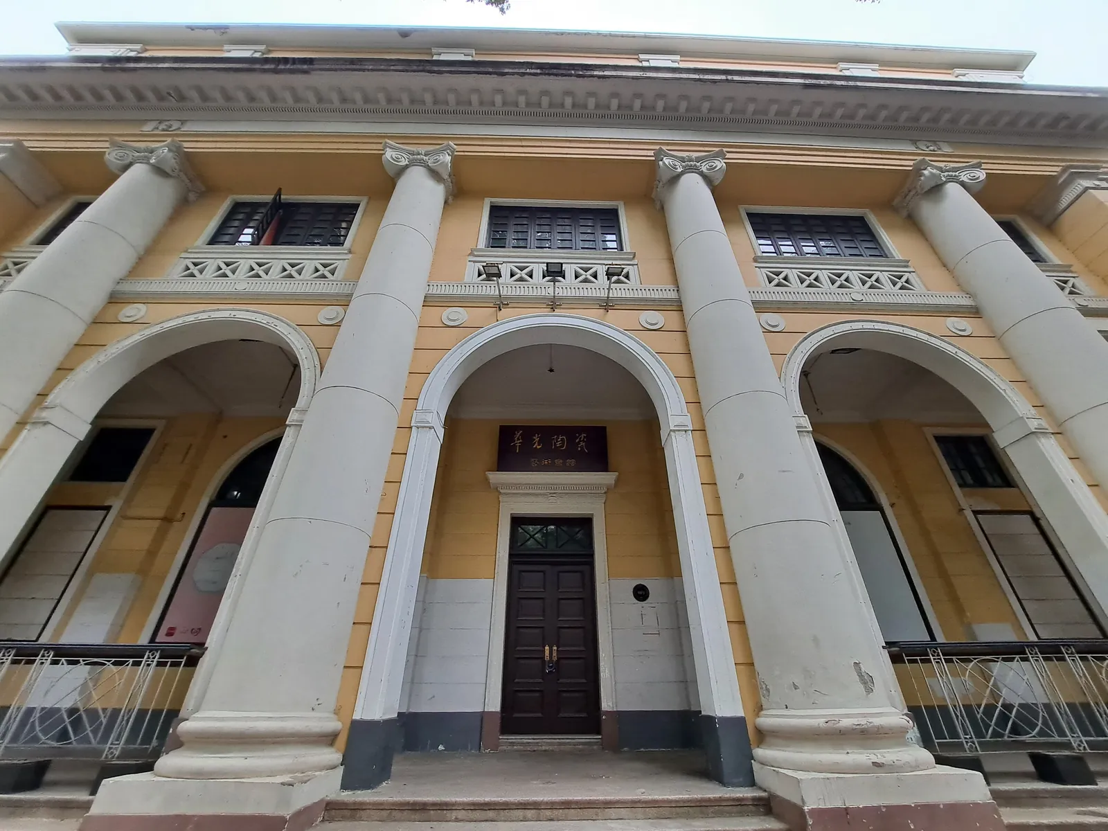 The bank’s entrance today: an arched doorway between giant columns, painted yellow and white.